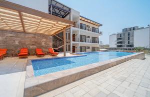 ein Pool mit orangefarbenen Stühlen und ein Gebäude in der Unterkunft Departamentos Ámbar in Santa Cruz Huatulco