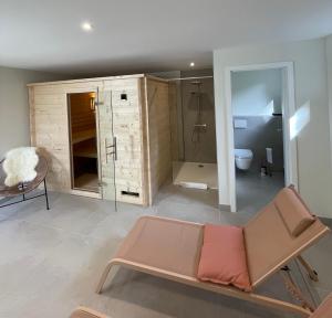 a bathroom with a shower and a couch in a room at Le Hêtre Rouge - Écureuil et Geai Charme & Spa Alsace in Barr