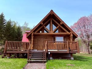 a log cabin with a large deck in the grass at Villa Rusutsu in Rusutsu