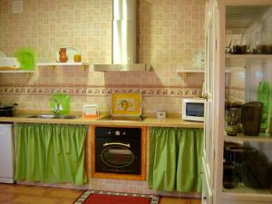 una cucina con tende verdi e una stufa di Casa Rural Dilamor a El Picazo