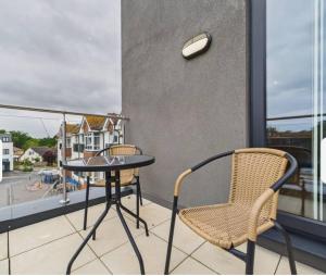 a balcony with a table and chairs and a window at Cooden Balcony Apartment in Bexhill