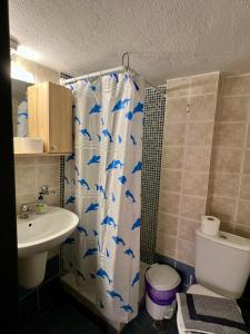 a bathroom with a shower curtain with a toilet and a sink at PELEKAN rooms and apartments Athina 33 in Pefkohori +22 photos