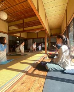 a group of people sitting on the floor of a building at SUNAORetreat奥白浜 in Minamiboso