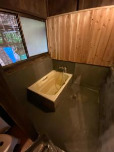 a bathroom with a tub and a window and a sink at SUNAORetreat奥白浜 in Minamiboso