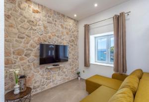 a living room with a couch and a tv on a stone wall at Apartments by the sea Cove Zastupac, Hvar - 8761 in Hvar