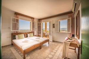 a bedroom with a bed and a table and windows at Dolce Vita Residence in Kalamaki