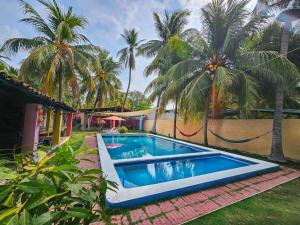 AcajutlaRancho Samba do Sol的棕榈树环绕的房子前的游泳池