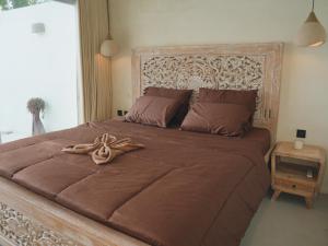 a bedroom with a large bed with a wooden headboard at Amada Penida Villa in Nusa Penida