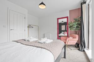 バーミンガムにあるLotus Haus - Wellington Homes - with off road Parkingの白いベッドルーム(ベッド1台、ピンクの椅子付)