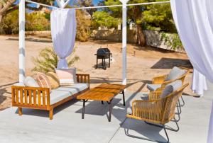 a porch with a couch and chairs and a table at Desert Dream Oasis - Spa, Cabana, Firepit, Disney and Hulu in Yucca Valley