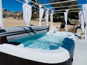 a jacuzzi tub on a patio with an umbrella at Desert Dream Oasis - Spa, Cabana, Firepit, Disney and Hulu in Yucca Valley