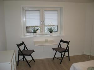 two chairs and a table in a room with two windows at Aalborg City Rooms ApS in Aalborg