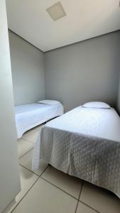 two beds in a room with white walls at Apartamento confortável e aconchegante in Montes Claros +1 photo