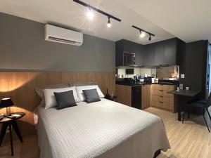 a bedroom with a large white bed and a kitchen at Studio moderno e novo perto do MAC - UNI Home 113 - Boa Viagem in Niterói