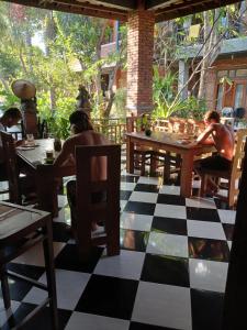 two men sitting at tables in a restaurant with a checkered floor at Dannyjuljolhomestay in Madawa