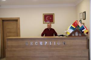 a man is sitting at a reception desk at Akpinar Hotel in Uzungöl
