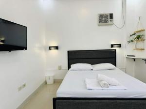a bedroom with a bed with white sheets and a flat screen tv at 4 bedroom with big pool villa near clark in Sampong