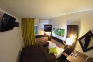 a hotel room with a bed and a television at A&H PRIVILÈGE Lyon Est - Saint Priest Eurexpo in Saint-Priest