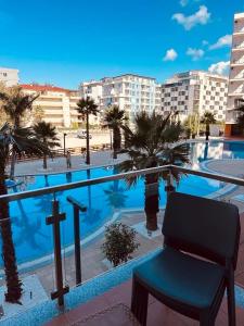 una silla junto a una piscina con palmeras en Jimmys Apartment, en Lezhë