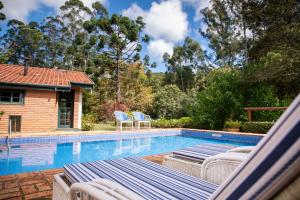 a swimming pool with lounge chairs next to a house at Pousada Barra do Bié in Cunha