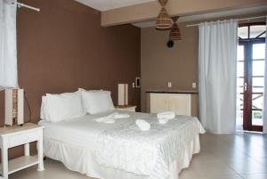 a bedroom with a large white bed with towels on it at Pousada Aruana in Canoa Quebrada