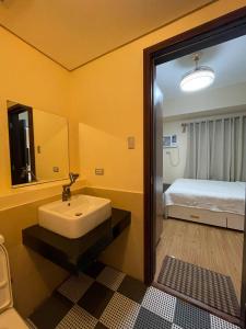 a bathroom with a sink and a mirror and a bed at The Radiance Manila Bay in Sampong