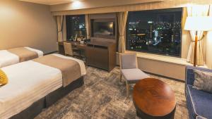 a hotel room with two beds and a desk and a window at Premier Hotel Nakajima Park Sapporo in Sapporo