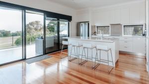 a kitchen with white cabinets and a counter with bar stools at Holiday of Perfect Strokes in Cape Schanck