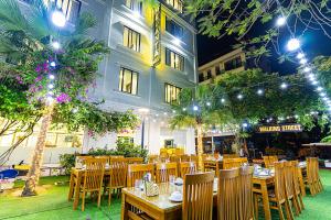 a restaurant with tables and chairs and a building at MELANTA HOTEL FLC SẦM SƠN in Sầm Sơn