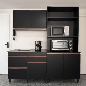 kuchnia z czarnymi szafkami i kuchenką mikrofalową w obiekcie 205 Atlântico Residence Vista Mar w mieście Fortaleza