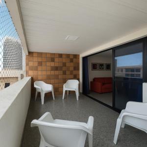 balkon z białymi krzesłami i czerwoną kanapą w obiekcie 205 Atlântico Residence Vista Mar w mieście Fortaleza