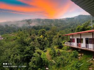 Un arcobaleno sopra una montagna con una casa di Shiv Shankar Resort a Phata