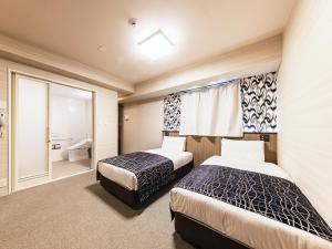 a hotel room with two beds and a bathroom at APA Hotel Nambaminami Daikokucho Ekimae in Osaka