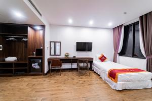 a bedroom with a bed and a desk and a tv at MELANTA HOTEL FLC SẦM SƠN in Sầm Sơn
