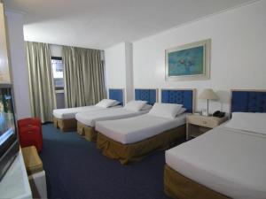 een hotelkamer met drie bedden en een televisie bij Hotel Supreme in Baguio