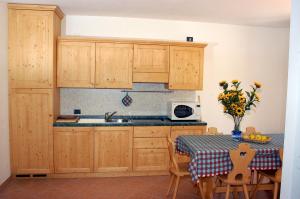 a kitchen with wooden cabinets and a table and a sink at Residence Alice in Celledizzo