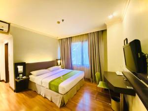 a hotel room with a bed and a flat screen tv at Grand Cemara Hotel in Jakarta
