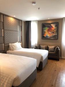 une chambre d'hôtel avec deux lits et un canapé dans l'établissement Sri U-Thong Grand Hotel, à Suphanburi