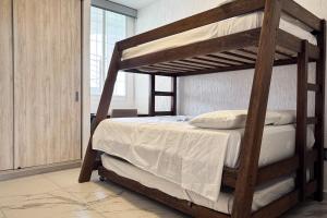 a bedroom with a bunk bed with white sheets at Departamento en Manzanillo a 5 min de la playa in Manzanillo