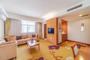 a living room with a couch and a tv at Lijiang Waika Hotel in Lijiang