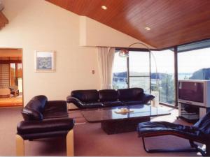 a living room with leather couches and a tv at Tomoyama Kanko Hotel in Shima