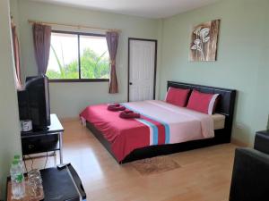 a bedroom with a bed with pink pillows and a tv at Sea beach Koh Larn 2 Hotel in Ko Larn