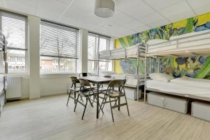 een slaapzaal met stapelbedden en een tafel en stoelen bij Dutchies Hostel in Amsterdam