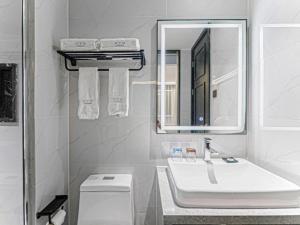 ein weißes Badezimmer mit Waschbecken und Spiegel in der Unterkunft Xana Hotelle Nanchang Honggutan in Nanchang + 175 Fotos