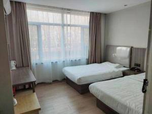 une chambre d'hôtel avec deux lits et une fenêtre dans l'établissement 7 Days Inn Tianjin Binhai Passenger Station Huabei Ceramics, à Binhai