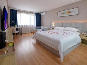 a bedroom with a large white bed with red flowers on it at danfeng kelly hotel in Dapeng