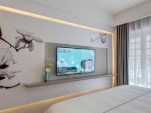 a bedroom with a flat screen tv on the wall at Magnotel Harbin Songbei Wanda Wenlvcheng in Harbin