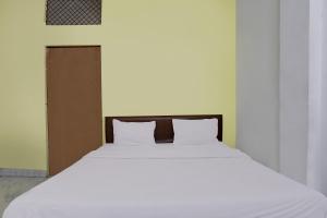 a white bed with two pillows in a room at Hotel O Raghav Residency in Ghaziabad