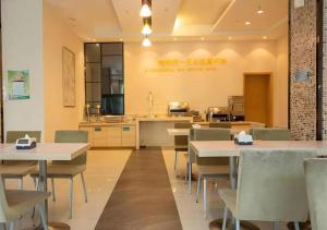 a restaurant with tables and chairs and a kitchen at City Comfort Inn Xiantao Avenue Wangzhou Bridge Wushang in Xiantao