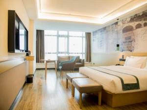 a hotel room with a bed and a desk and a chair at City Comfort Inn Wanning Wan'An Avenue High Speed Railway Station in Wanning